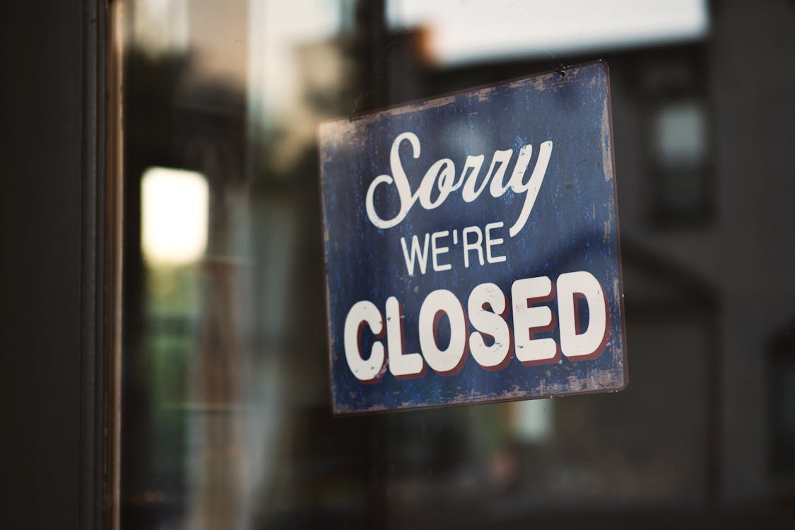 A closed storefront with a "sorry we’re closed" sign on the door.