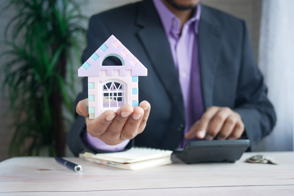 A professional appraiser holding a miniature house